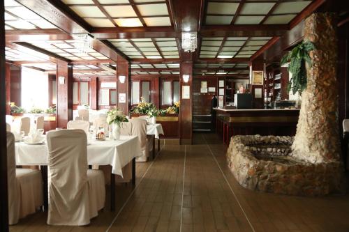un ristorante con tavoli bianchi e un albero al centro di B&B Vila Bela Ruza a Sremska Mitrovica
