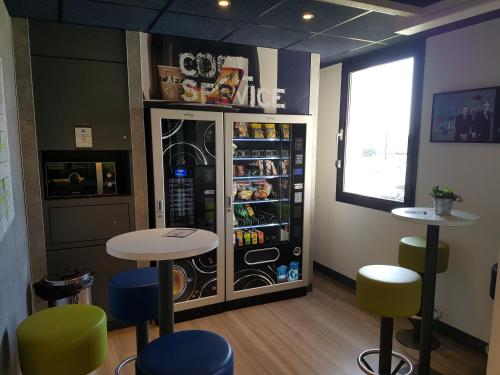 a restaurant with a refrigerator and tables and chairs at Ibis Budget Dole-Choisey in Dole
