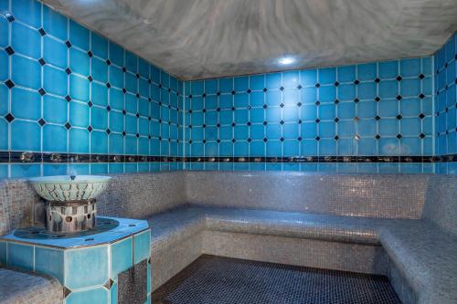 a blue tiled room with a tub and a vase at Wellness & Relax Hotel Milderer Hof in Neustift im Stubaital