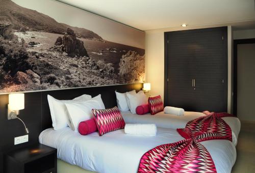 two beds in a hotel room with red and white pillows at Appart'hotel Souani (Al Hoceima Bay) in Al Hoceïma