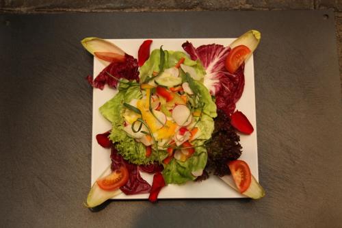 a white plate with a salad on a table at Apart Rustica in Kaunertal