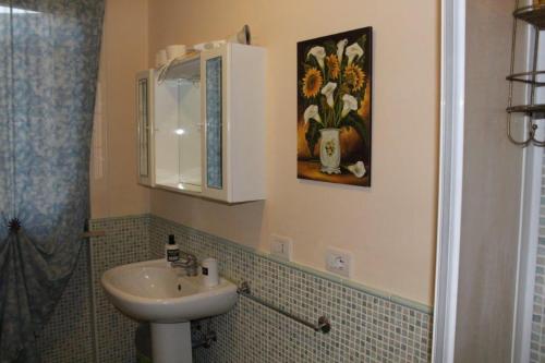a bathroom with a sink and a painting of flowers at AFFITTACAMERE La Tartaruga in Civitanova Marche