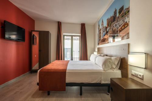 Habitación de hotel con cama y TV de pantalla plana. en Baluart Apartments en Cáceres
