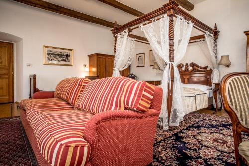 a living room with a couch and a bed at Hotel Dvur Hoffmeister in Velké Číčovice