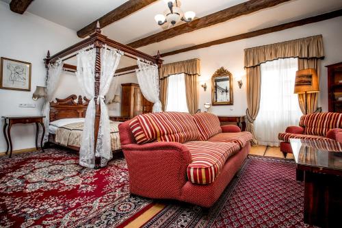 a living room with a couch and a bed at Hotel Dvur Hoffmeister in Velké Číčovice