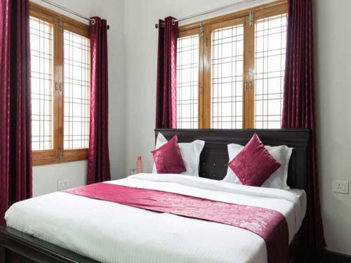 a bedroom with a large bed with red curtains at Fresh Living Prime Banjara in Hyderabad