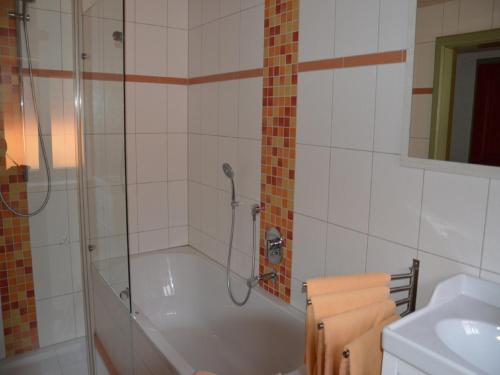 uma casa de banho com um chuveiro, uma banheira e um lavatório. em Landgasthaus Mittelallgäu em Betzigau