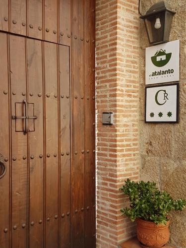 a wooden door to a building with a potted plant at El Atalanto in Madrigal de la Vera
