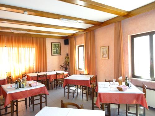 a dining room with tables and chairs and windows at Hotel Galles in Paluzza
