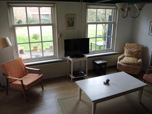 Una sala de estar con televisión, mesa y sillas. en Ferienhaus Gapinge Walcheren Zeeland, en Veere