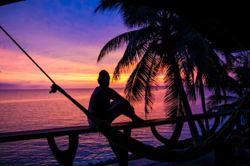 a person sitting on a hammock watching the sunset at Tintipan Cabana SalSiPuedes in Tintipan Island