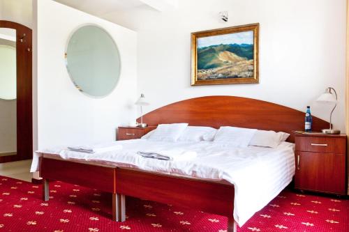 a bedroom with a large bed with a wooden headboard at Villa Park in Bukowina Tatrzańska