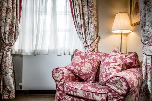a pink chair sitting in front of a window at Hotel Dvur Hoffmeister in Velké Číčovice
