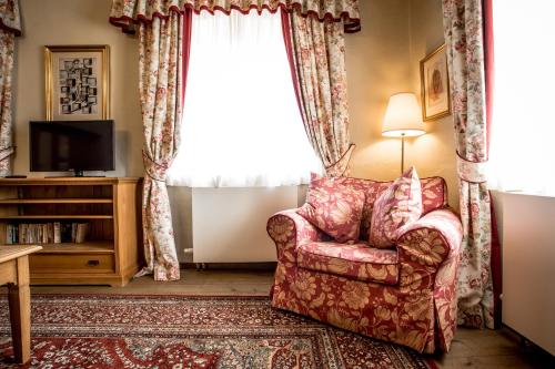 a living room with a chair and a window at Hotel Dvur Hoffmeister in Velké Číčovice