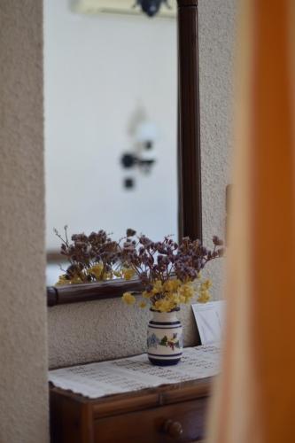 a vase with flowers on a table in front of a mirror at Pension Felippe in Pythagoreio