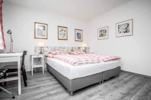 a white bedroom with a bed and a desk at Hotel Dvur Hoffmeister in Velké Číčovice