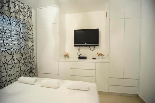 Dieses weiße Zimmer verfügt über ein Bett und einen TV. in der Unterkunft City Resort Palmore in Eilat