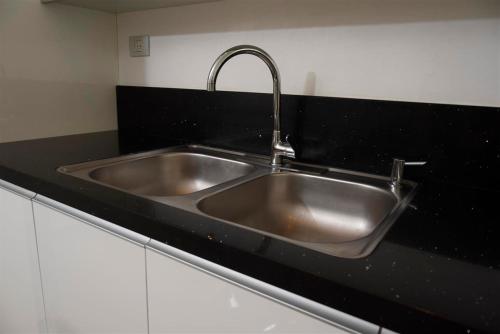 eine Küchenspüle aus Edelstahl in einer schwarzen Arbeitsplatte in der Unterkunft City Resort Palmore in Eilat