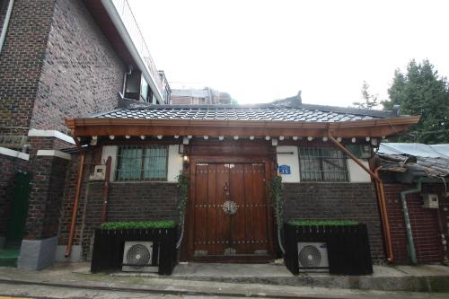 uma casa de tijolos com uma porta de madeira com dois bancos em ICOS Guesthouse 1 - Female Only em Seul