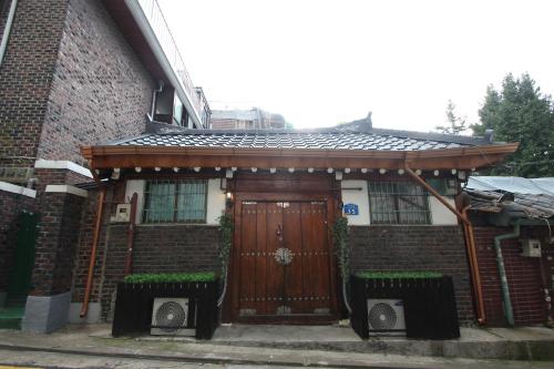 a brick house with a wooden door with two benches at ICOS Guesthouse 1 - Female Only in Seoul