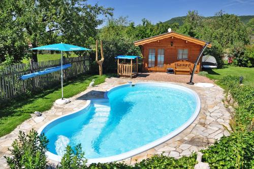 a swimming pool with an umbrella and a cabin at Pension "AM RENNSTEIG" in Eisenach