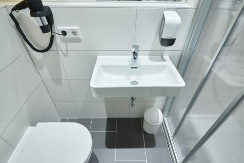 biała łazienka z umywalką i telefonem w obiekcie McDreams Hotel Düsseldorf-City w mieście Düsseldorf
