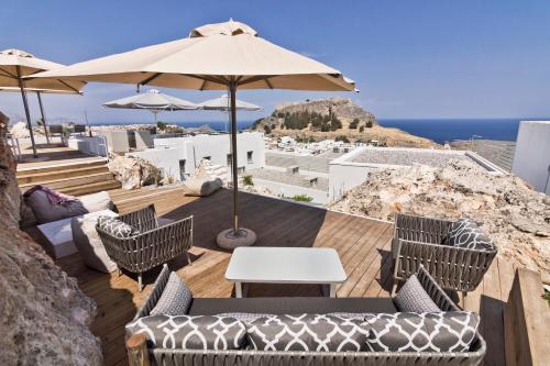 a patio with chairs and tables and an umbrella at Lindos Comfy Suites in Lindos
