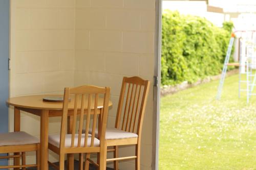 a table and two chairs sitting next to a window at Broadway Motel & Miro Court Villas in Matamata