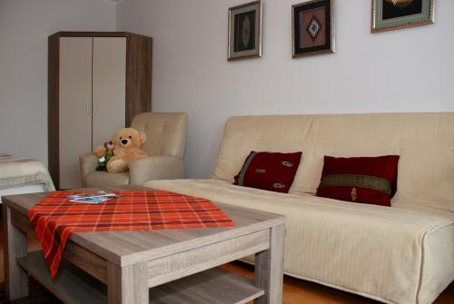 a living room with a couch and a teddy bear at Apartment AMUR in Kraków