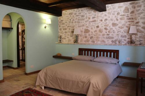 a bedroom with a bed and a stone wall at Agriturismo Casale Montebello in Monteleone di Spoleto