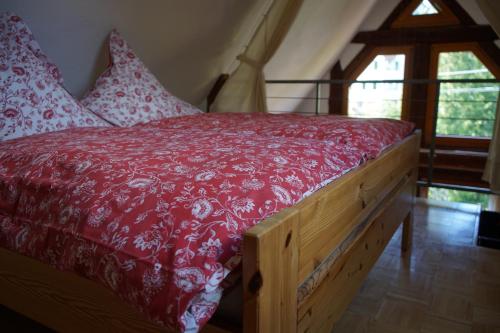 a bed with a red comforter and pillows at Ferienwohnung del Arte in Baiersbronn