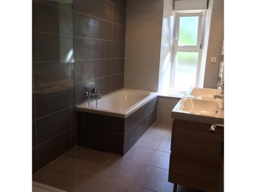 a bathroom with a tub and a sink at La Grange du Lac de Cantalès in Lacapelle-Viescamp