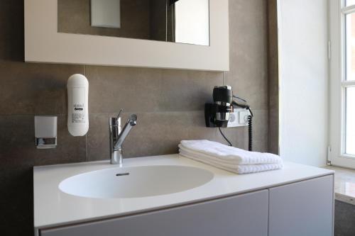 a bathroom with a white sink and a mirror at BA Hotel by WMM Hotels in Babenhausen