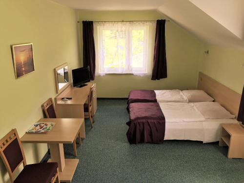 シュクラルスカ・ポレンバにあるPokoje Gościnne w Dolinie Szczęściaのベッドとデスクが備わるホテルルームです。