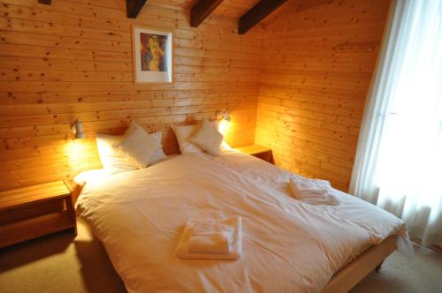 レ・ジェにあるChalet Pandaの白いベッド1台が備わる木製の壁のベッドルーム1室