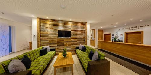 a lobby with a couch and a table and a tv at Almhotel Kärnten in Sonnenalpe Nassfeld