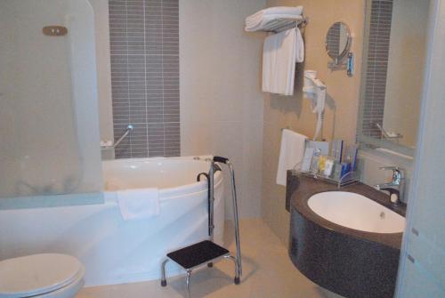 a bathroom with a tub and a toilet and a sink at Costa Del Sol Hotel by Arabian Link in Kuwait