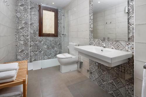 uma casa de banho branca com um lavatório e um WC em El Portal de Alquezar em Alquézar