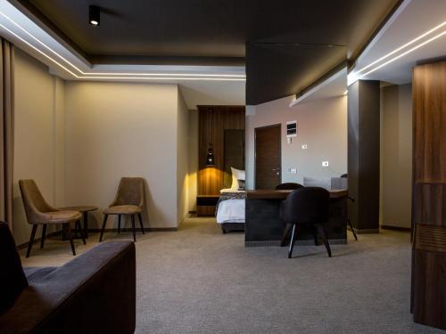 Habitación de hotel con cama y sillas en Hotel Ideo Lux, en Niš