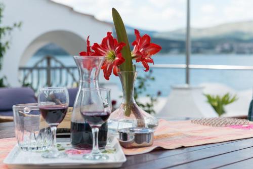 una mesa con dos copas de vino y un jarrón con flores rojas en Apartment Marin en Trogir
