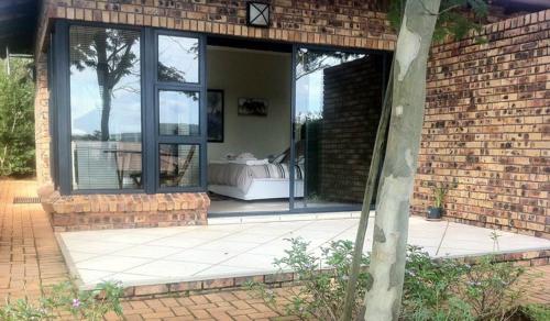 a brick house with a patio with a bed in the window at Longmere Cottages in White River