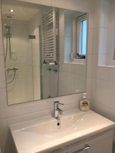 a white bathroom with a sink and a mirror at Salt Life Beachhouse in Noordwijk aan Zee