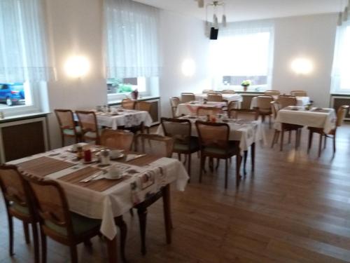 a dining room with tables and chairs with white tablecloths at Pension Cecilie in Braunlage