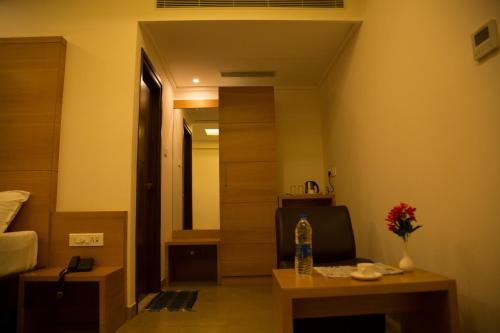 a room with a bed and a table with a vase of flowers at Hotel Grand Tree in Coimbatore