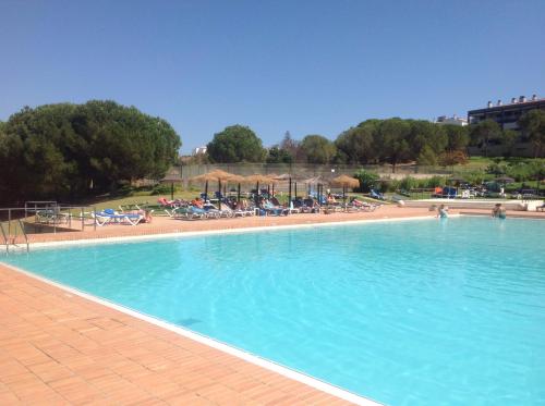 a large blue swimming pool with chairs and umbrellas at Férias Lagos in Lagos