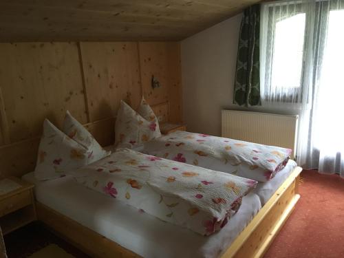 a bedroom with a bed with white sheets and pillows at Landhaus Kuen in Huben