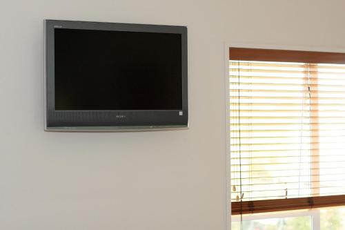 a flat screen tv on a wall next to a window at Broadway Motel & Miro Court Villas in Matamata