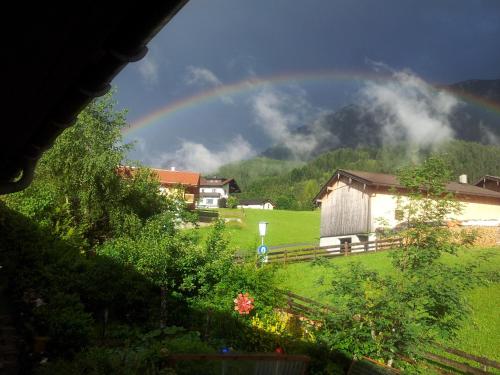 a rainbow over a green field with a house at Badhaus in Achenkirch