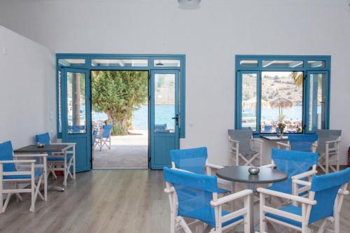 una sala da pranzo con sedie blu, tavoli e finestre di Delfini Hotel a Skála