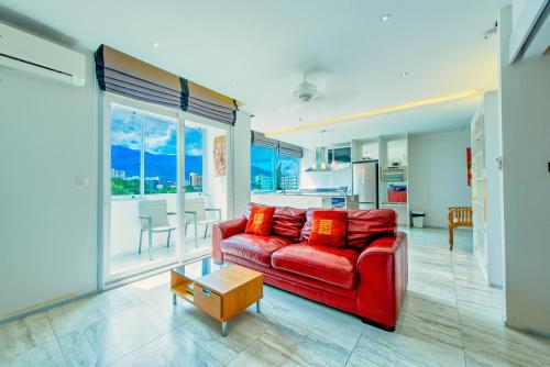 a living room with a red couch and a kitchen at Viengping Mansion Chiang Mai - Heart of Nimman, Shopping & Cafes in Chiang Mai